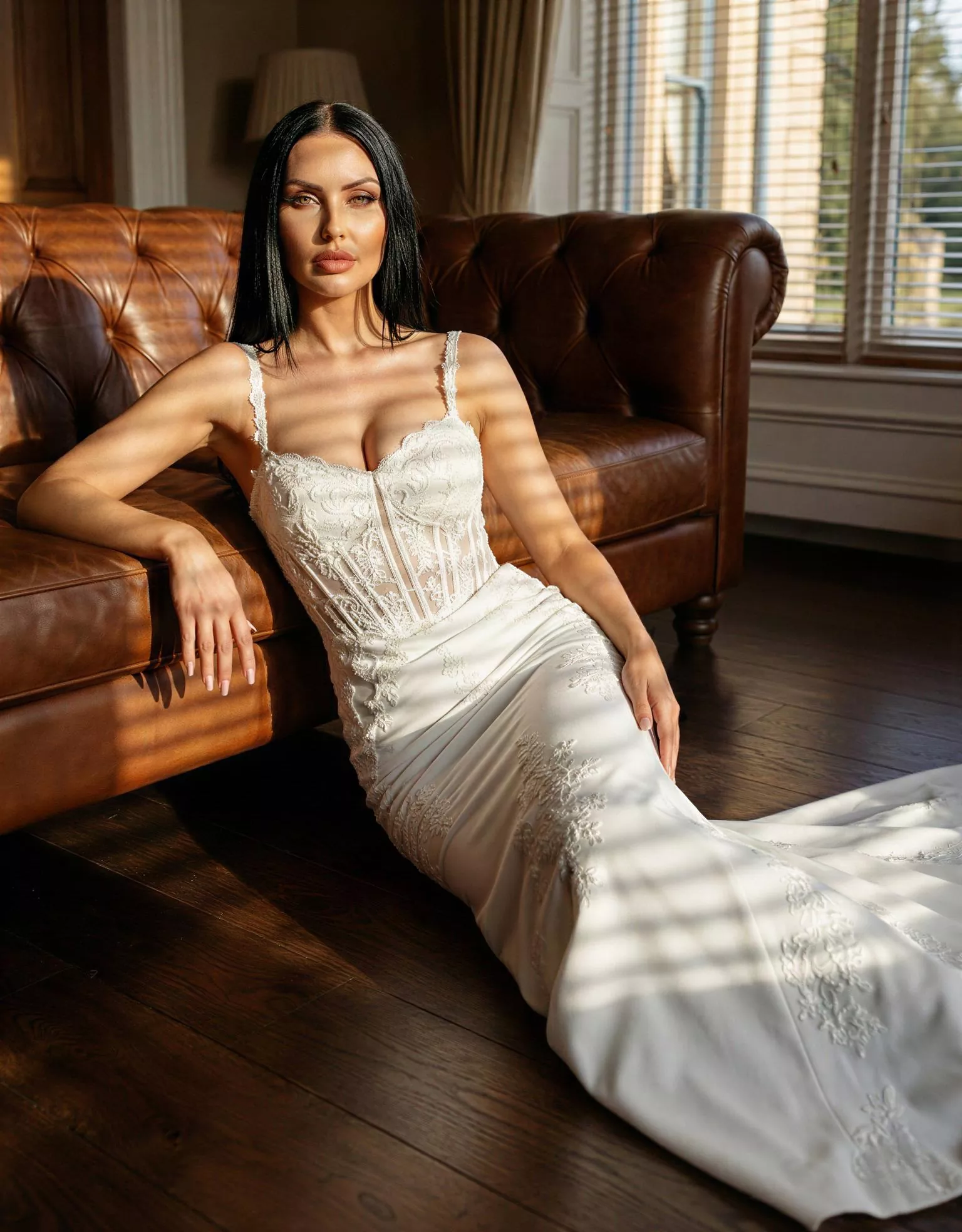 Vestido de novia Angelina pose editorial sofá, escote corazón, espalda recta, corte sirena,encaje, crepé Atelier Boheme