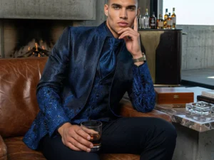 Traje de novio Enki, pose sentado, color azul noche y azul cobalto tela jacquard, cuello mao de ceremonia, Atelier Masculini