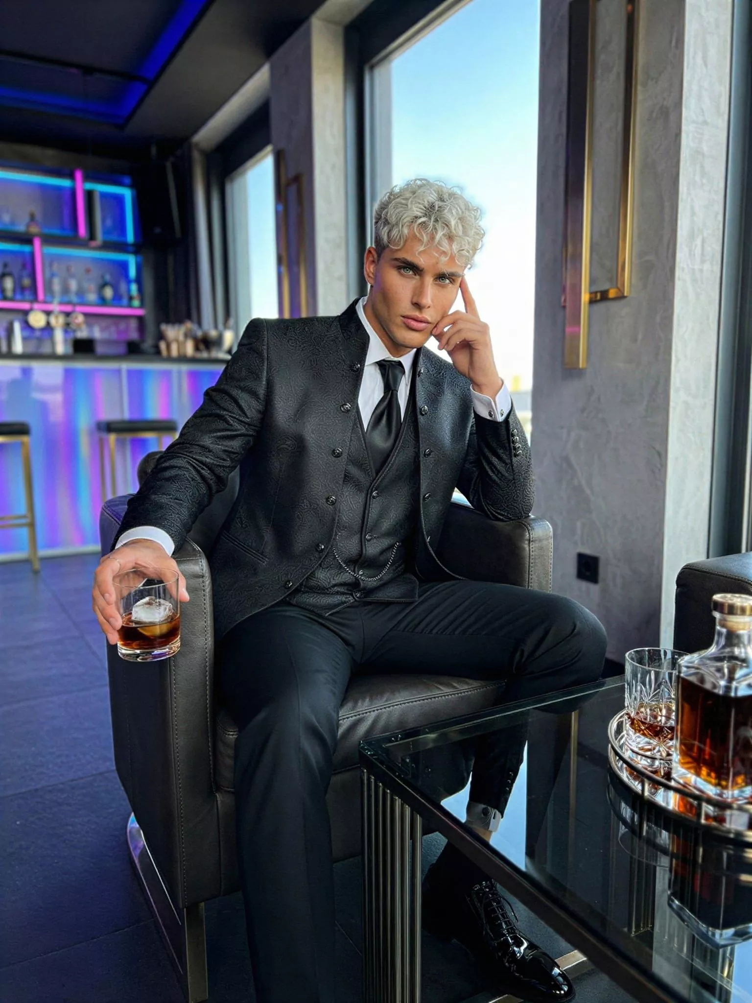 Traje de novio Radan, pose sentado, color negro y texturizado jacquard, cuello mao de ceremonia con doble botonera, Atelier Masculini